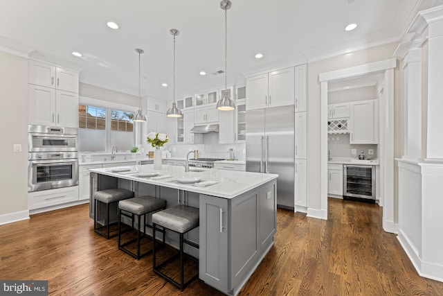 kitchen featuring beverage cooler, appliances with stainless steel finishes, white cabinets, and under cabinet range hood