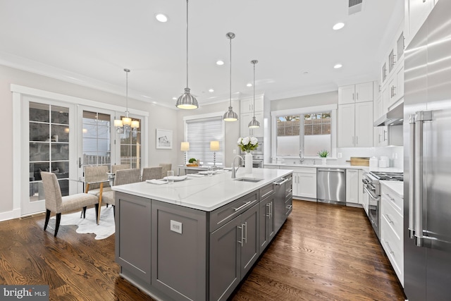 kitchen featuring high end appliances, gray cabinetry, white cabinetry, a sink, and under cabinet range hood