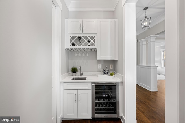 bar with wine cooler, indoor wet bar, crown molding, decorative columns, and a sink