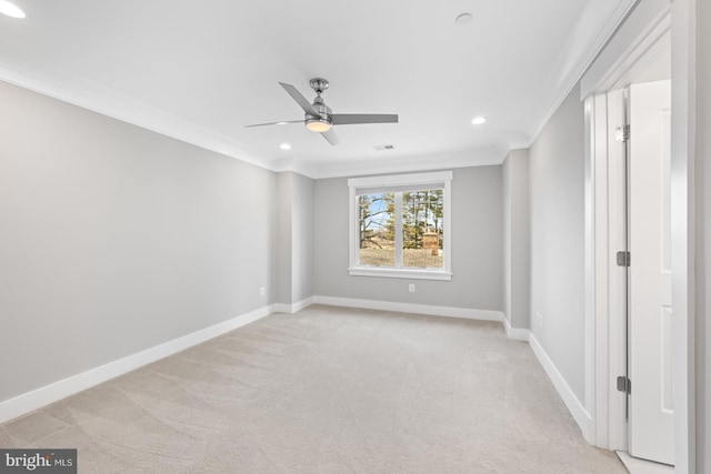 unfurnished room featuring light carpet, a ceiling fan, baseboards, and crown molding