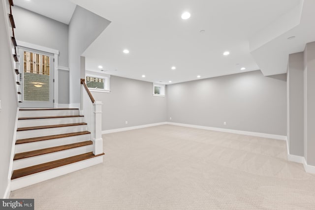 below grade area with light carpet, stairway, baseboards, and recessed lighting