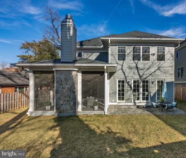 rear view of house with a lawn, a sunroom, a chimney, fence, and a patio area