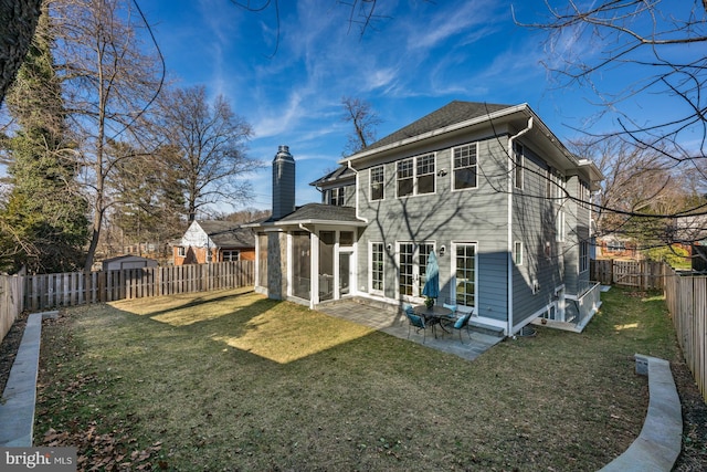 back of house with a patio area, a lawn, a chimney, and a fenced backyard