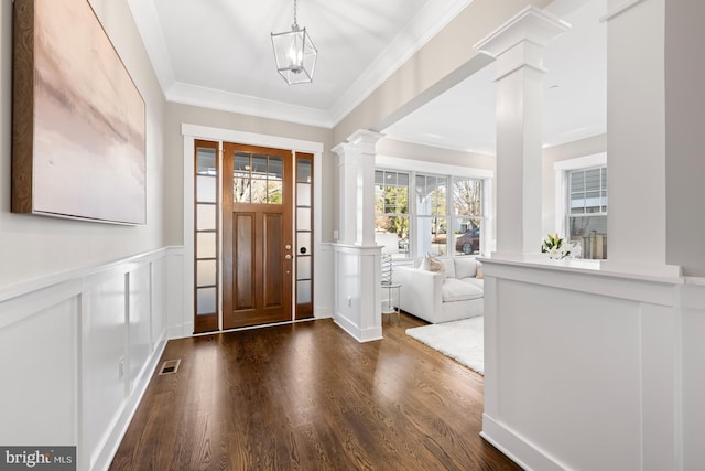 entryway featuring a wainscoted wall, wood finished floors, visible vents, ornamental molding, and decorative columns