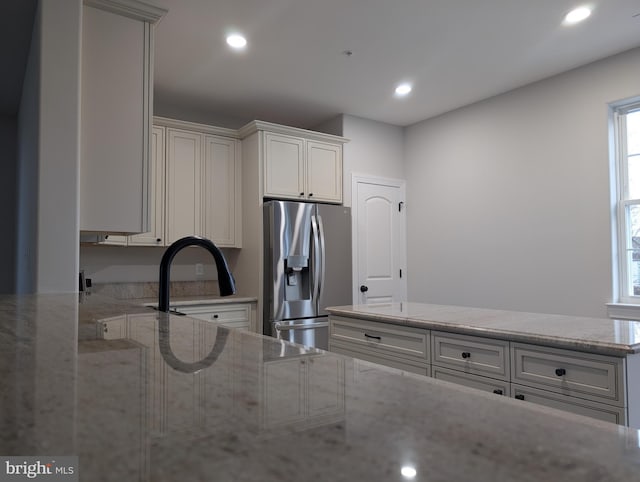 kitchen with light stone countertops, recessed lighting, and stainless steel refrigerator with ice dispenser