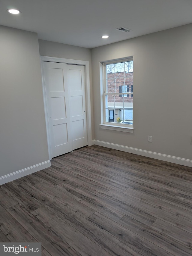 unfurnished bedroom with a closet, visible vents, baseboards, recessed lighting, and dark wood-style floors