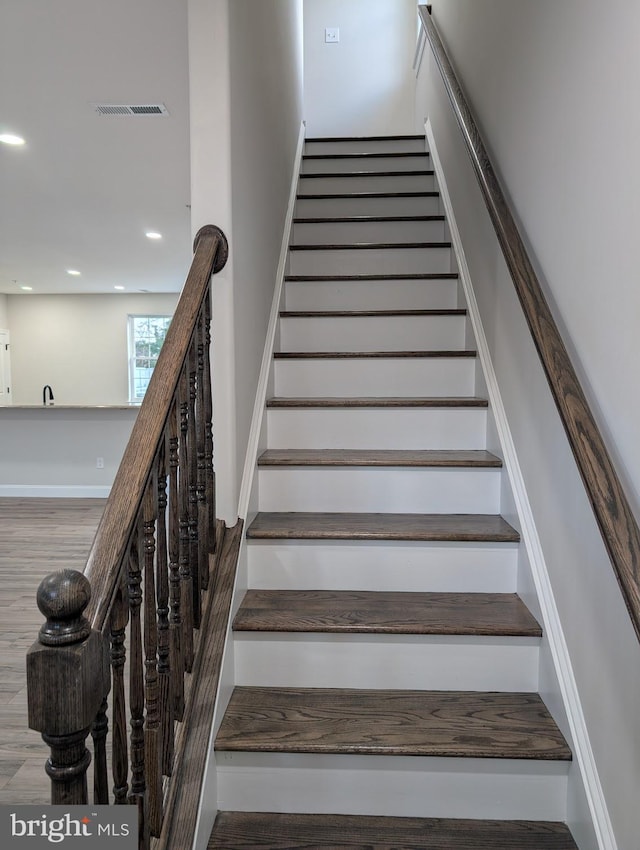 stairs with visible vents, wood finished floors, and recessed lighting