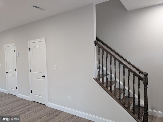 stairs featuring baseboards, visible vents, and wood finished floors