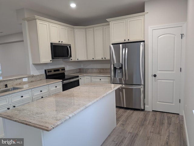 kitchen with a kitchen island, light stone countertops, stainless steel appliances, light wood-style floors, and recessed lighting