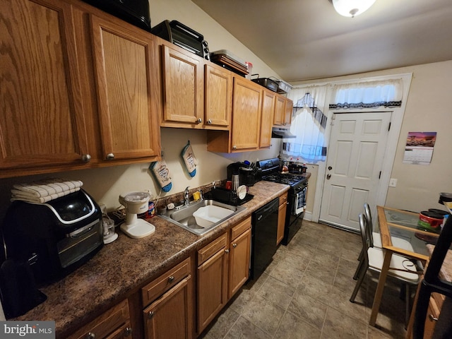 kitchen featuring dark countertops, brown cabinetry, a sink, under cabinet range hood, and black appliances