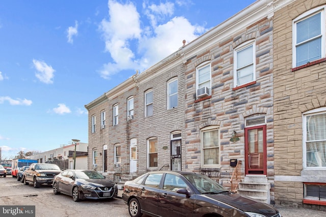 townhome / multi-family property with cooling unit and stone siding