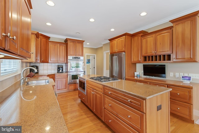 kitchen featuring light stone counters, stainless steel appliances, a sink, a kitchen island, and ornamental molding