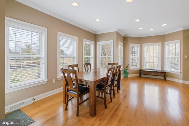 dining area featuring light wood finished floors, plenty of natural light, visible vents, and ornamental molding