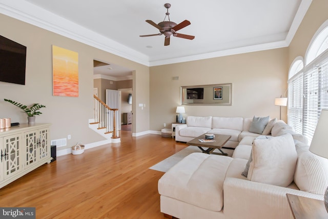 living room featuring crown molding, visible vents, wood finished floors, baseboards, and stairs