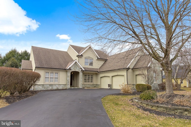 view of front of property with a garage, stone siding, driveway, and stucco siding