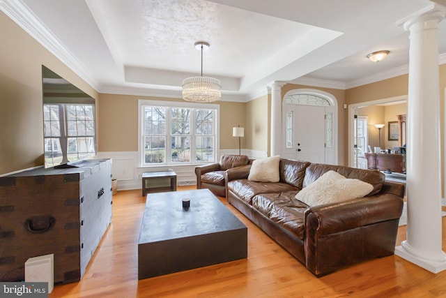 living area featuring a tray ceiling, wainscoting, and decorative columns