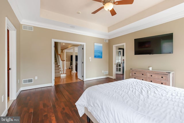 bedroom with hardwood / wood-style flooring, baseboards, visible vents, and a raised ceiling