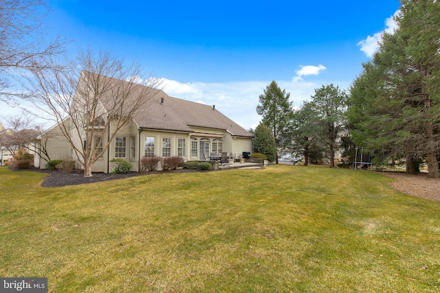 rear view of property featuring stucco siding, a shingled roof, a lawn, and a patio