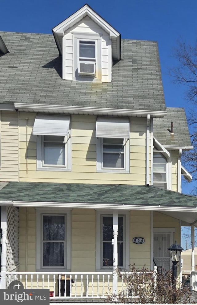 view of front of house with cooling unit, roof with shingles, and a porch