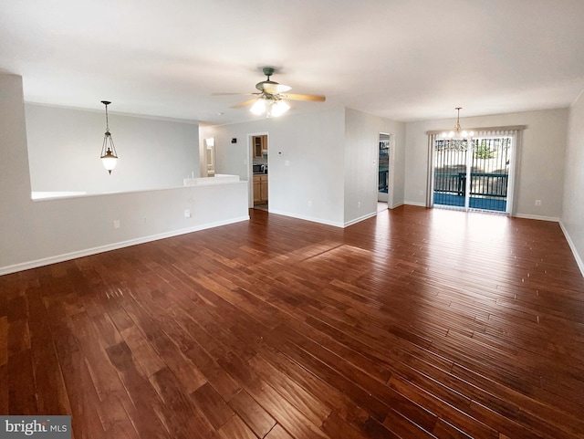 unfurnished living room featuring baseboards, dark wood-style flooring, and ceiling fan with notable chandelier