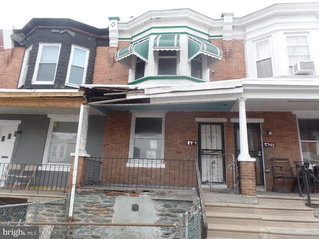 townhome / multi-family property with covered porch and brick siding