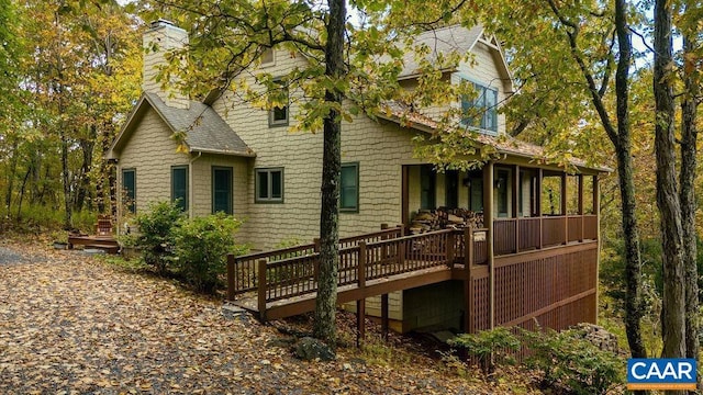 back of house featuring a shingled roof, a chimney, and a deck