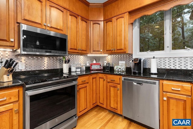 kitchen with light wood finished floors, tasteful backsplash, appliances with stainless steel finishes, and brown cabinetry