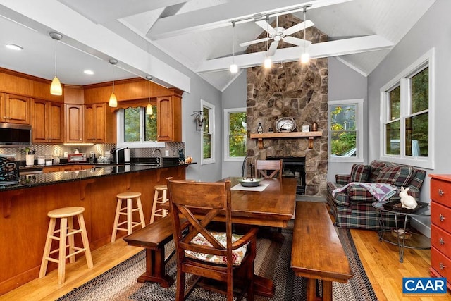 dining space featuring vaulted ceiling with beams, light wood-style floors, and plenty of natural light