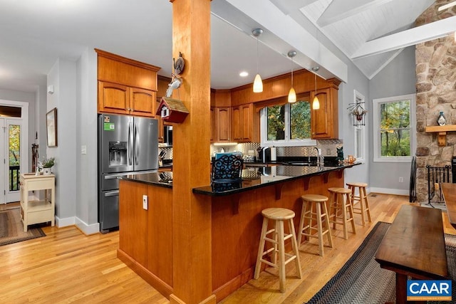 kitchen featuring lofted ceiling with beams, a healthy amount of sunlight, tasteful backsplash, and stainless steel fridge with ice dispenser