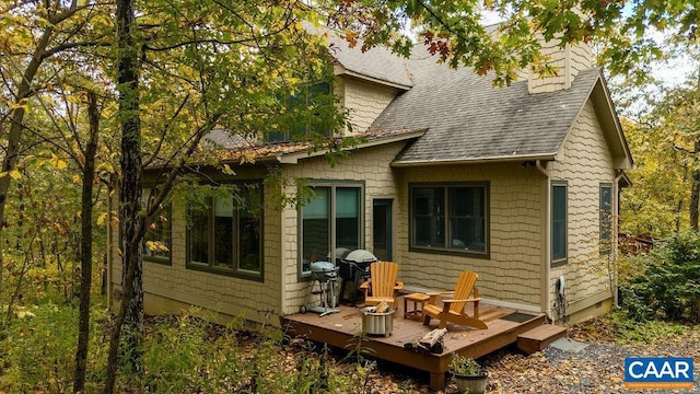 back of property with a shingled roof and a wooden deck