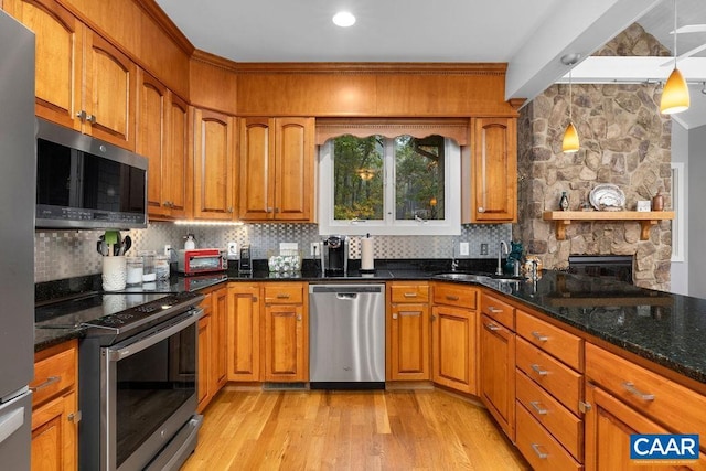 kitchen with dark stone counters, stainless steel appliances, backsplash, and brown cabinets