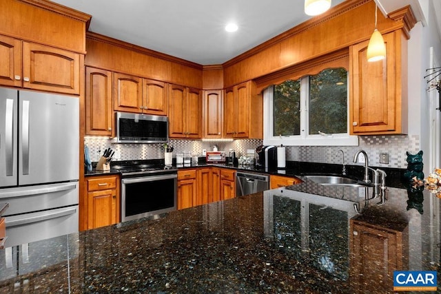 kitchen featuring a sink, appliances with stainless steel finishes, brown cabinets, dark stone counters, and tasteful backsplash