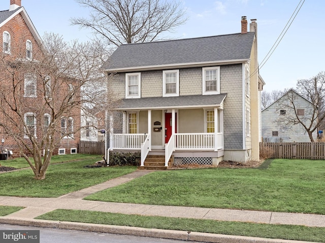 view of front of property featuring covered porch, a front lawn, a chimney, and a shingled roof