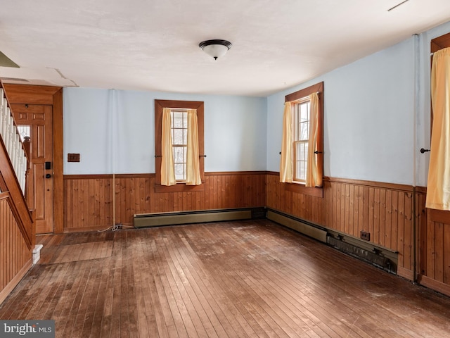 spare room with wood walls, wood-type flooring, stairway, and wainscoting