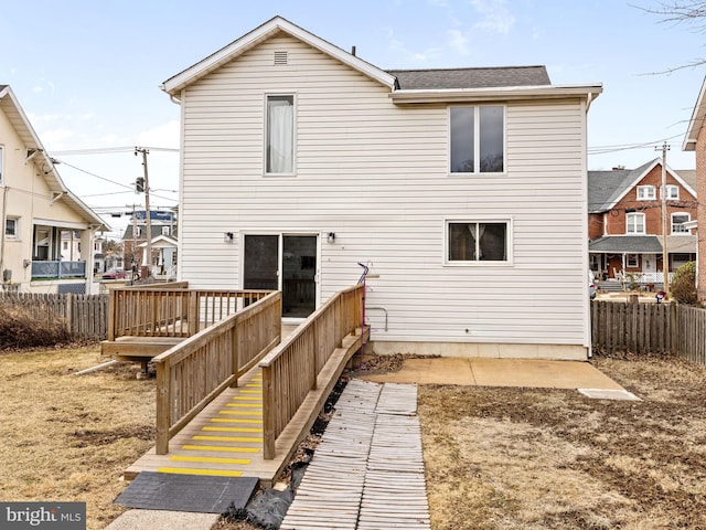 rear view of house featuring fence and a wooden deck