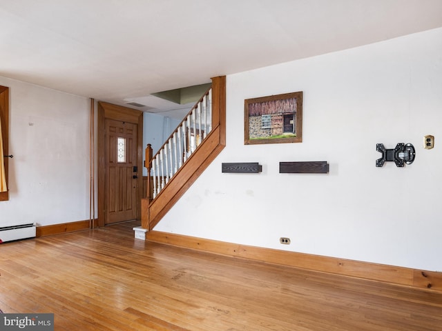 entrance foyer with stairway, a baseboard radiator, wood finished floors, and baseboards