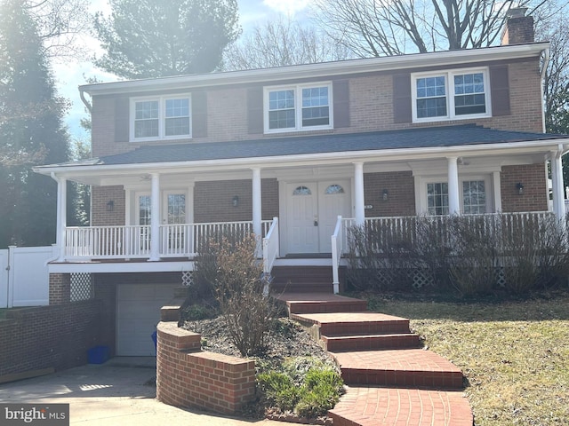 view of front of home featuring a porch, an attached garage, a chimney, concrete driveway, and brick siding