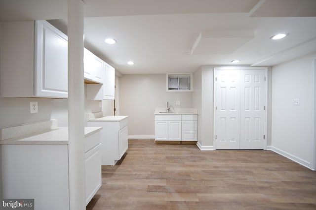 clothes washing area with light wood-style floors, recessed lighting, a sink, and baseboards