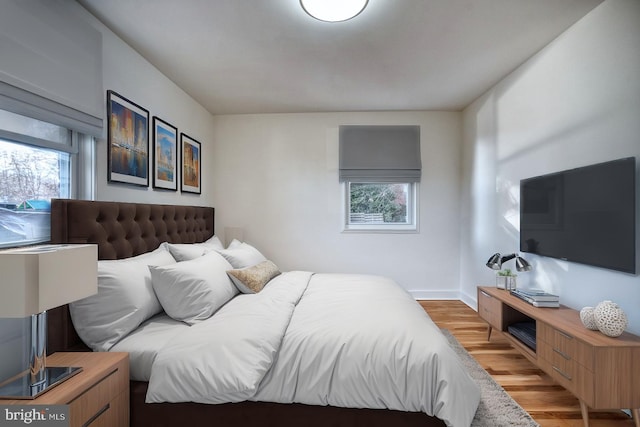 bedroom with baseboards, multiple windows, and light wood finished floors