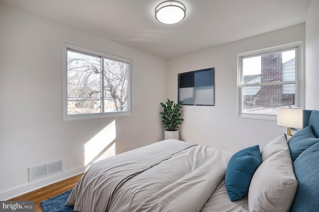 bedroom featuring visible vents, baseboards, and wood finished floors