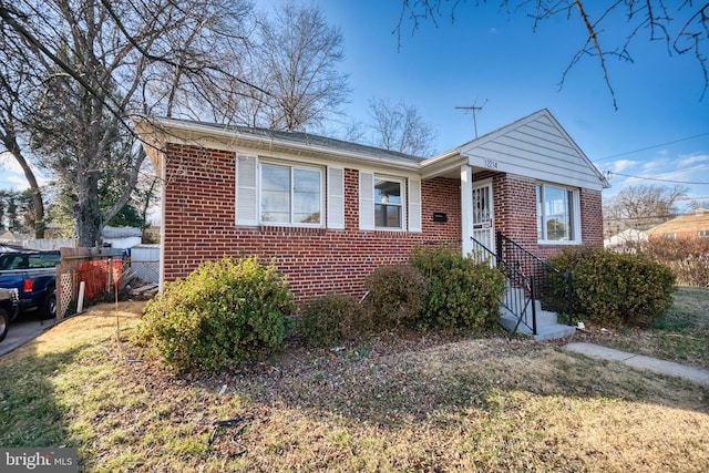 view of front facade with entry steps, a front yard, fence, and brick siding