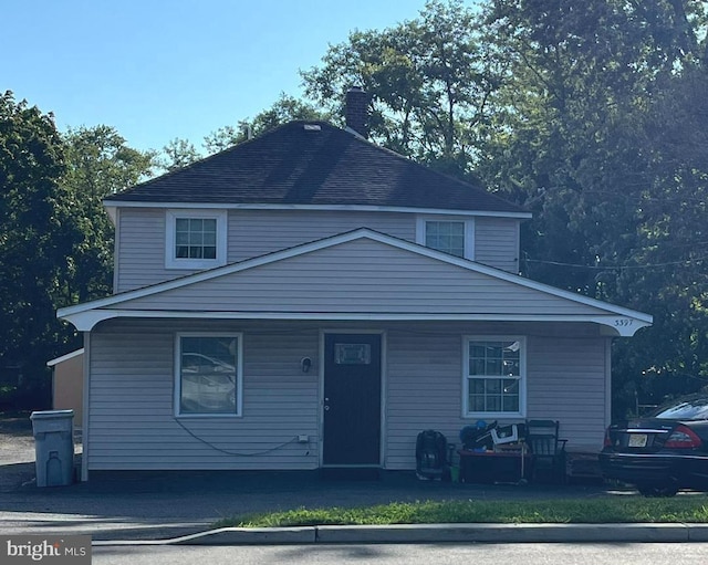 view of front of home featuring a porch, a chimney, and a shingled roof