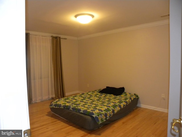 bedroom featuring light wood-style floors, baseboards, and ornamental molding