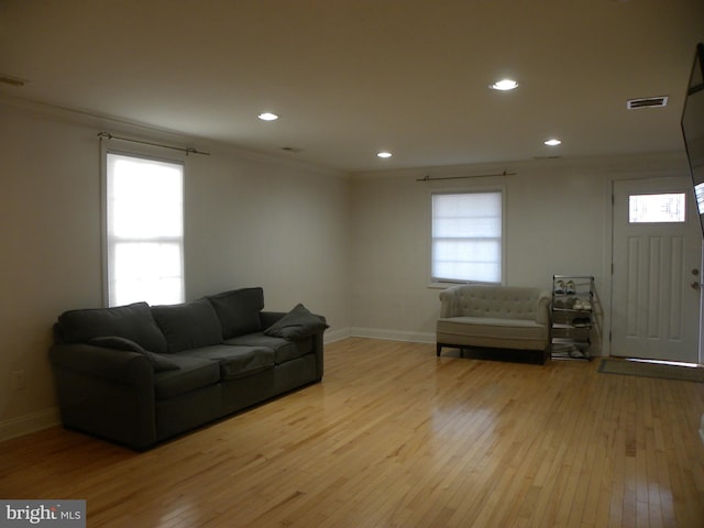 living room with visible vents, a healthy amount of sunlight, crown molding, and wood-type flooring