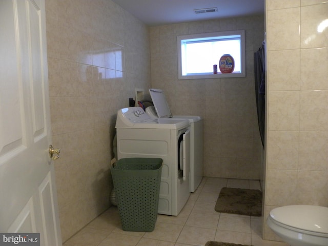 laundry area with visible vents, light tile patterned floors, laundry area, independent washer and dryer, and tile walls