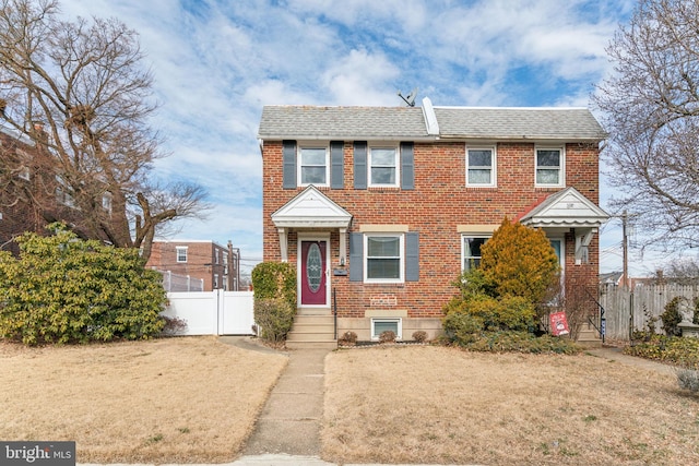 view of front facade with brick siding, fence, and a gate