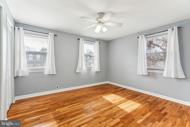 empty room with a healthy amount of sunlight, light wood finished floors, and baseboards