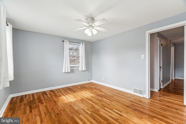 empty room featuring light wood finished floors, visible vents, and baseboards