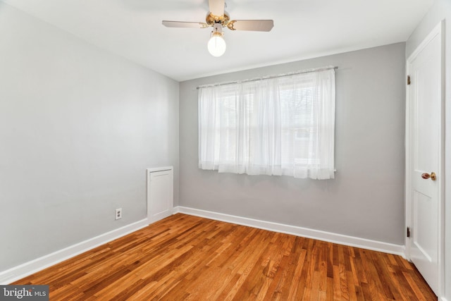 unfurnished room with ceiling fan, wood finished floors, and baseboards