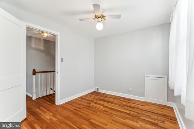 empty room with ceiling fan, visible vents, baseboards, and wood finished floors